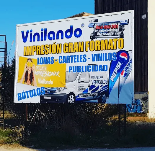 Valla publicitaria con lona impresa de gran formato junto a una carretera