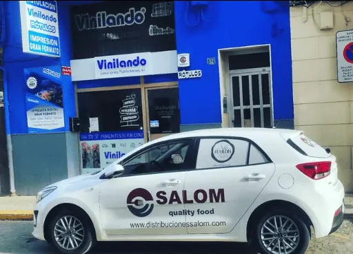 Coche blanco rotulado para Salom quality food frente al taller