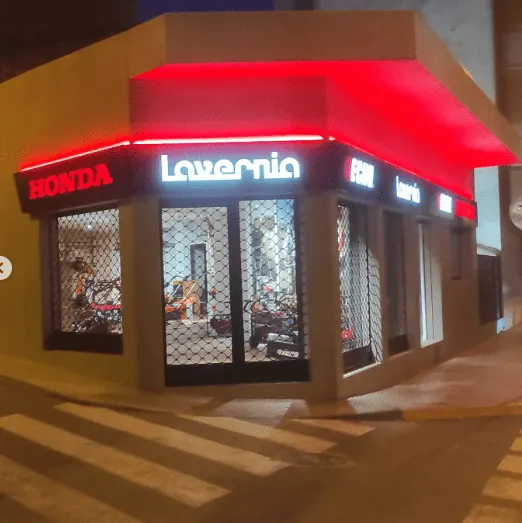 Rótulo luminoso LED rojo y blanco en la fachada de un comercio de esquina